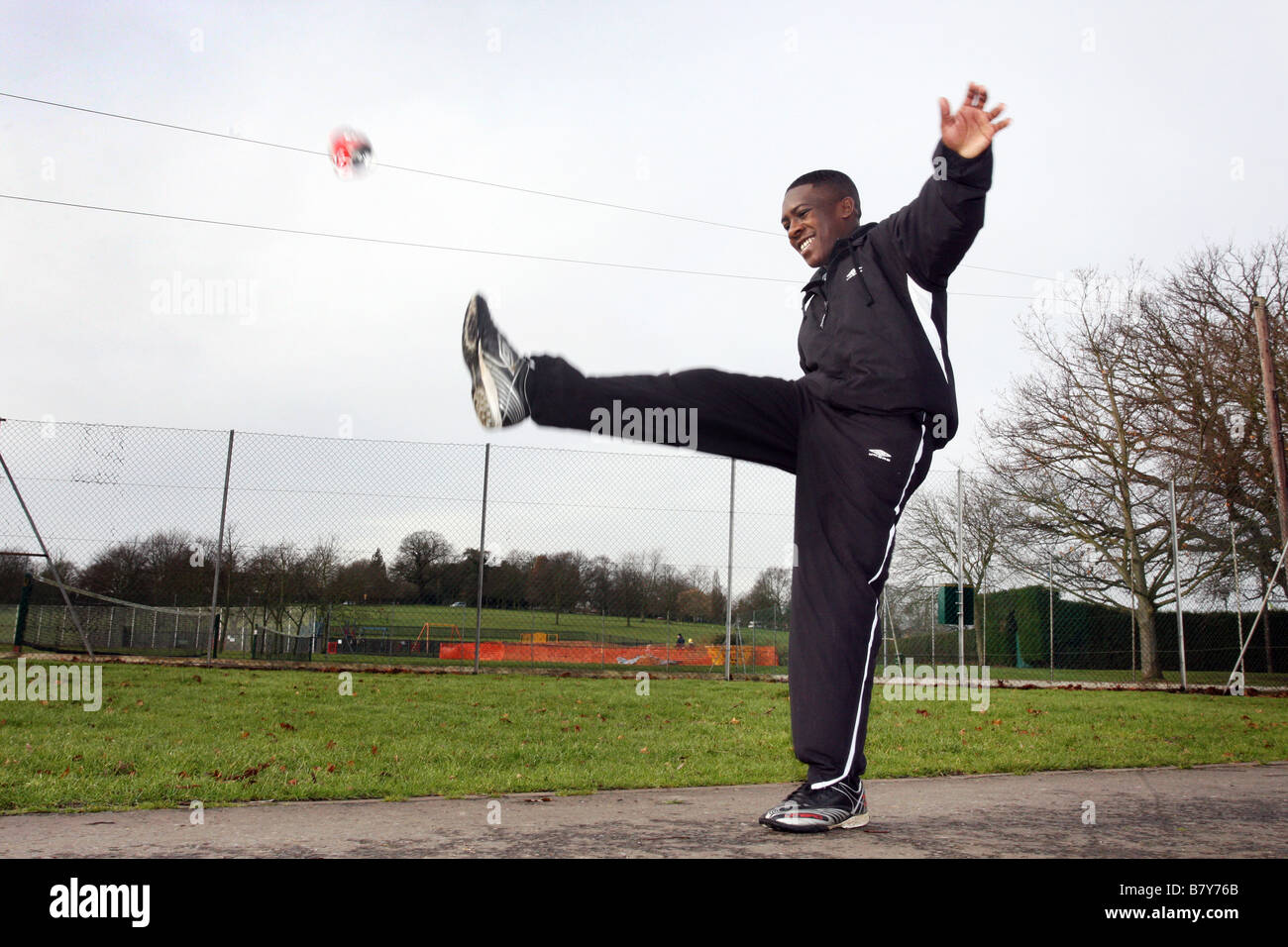 Young man kicking a can in the park as if playing football or rugby