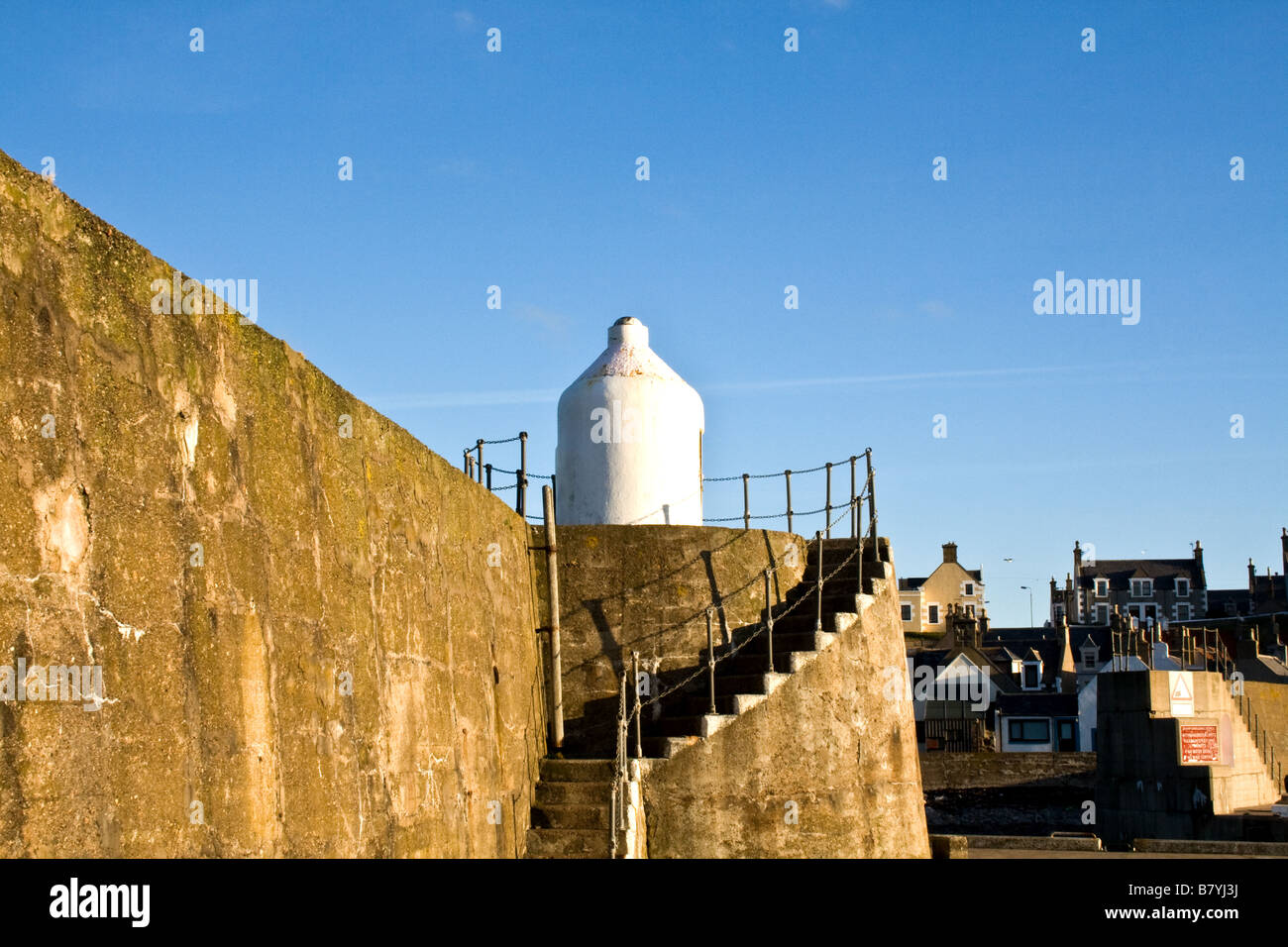 Small signal lamp with spiral staircase by a stone wall in Findochty, Scotland Stock Photo