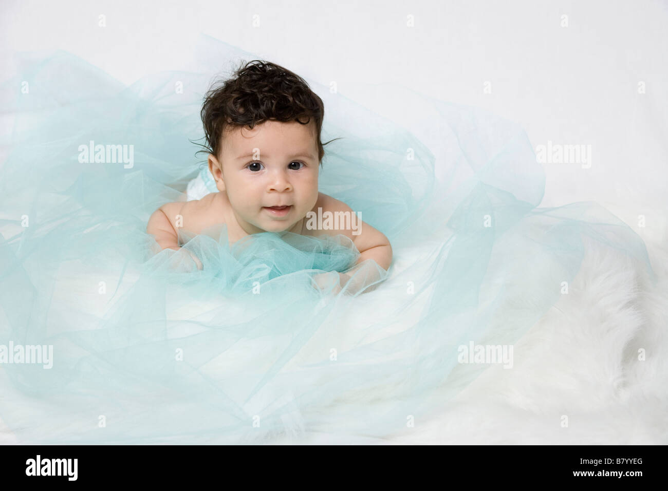 Latin baby boy wrapped by a silk blue material representing clouds Stock Photo