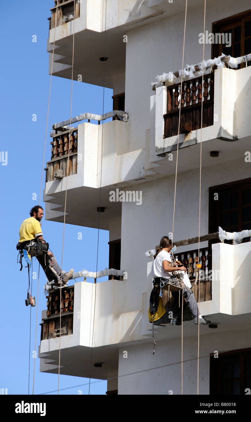 Workmen dangle from safety ropes to decorate the exterior of a high building in Icod town centre Tenerife Canary Islands Stock Photo