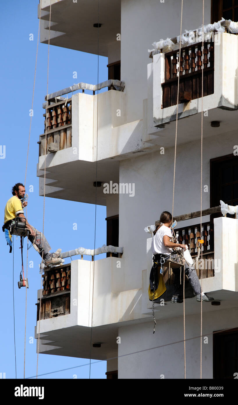 Workmen dangle from safety ropes to decorate the exterior of a high building in Icod town centre Tenerife Canary Islands Stock Photo