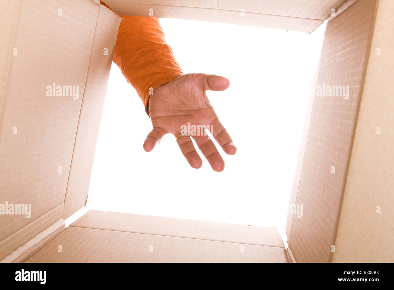 inside view of cardboard box with a hand trying to reach the content (selective focus) Stock Photo