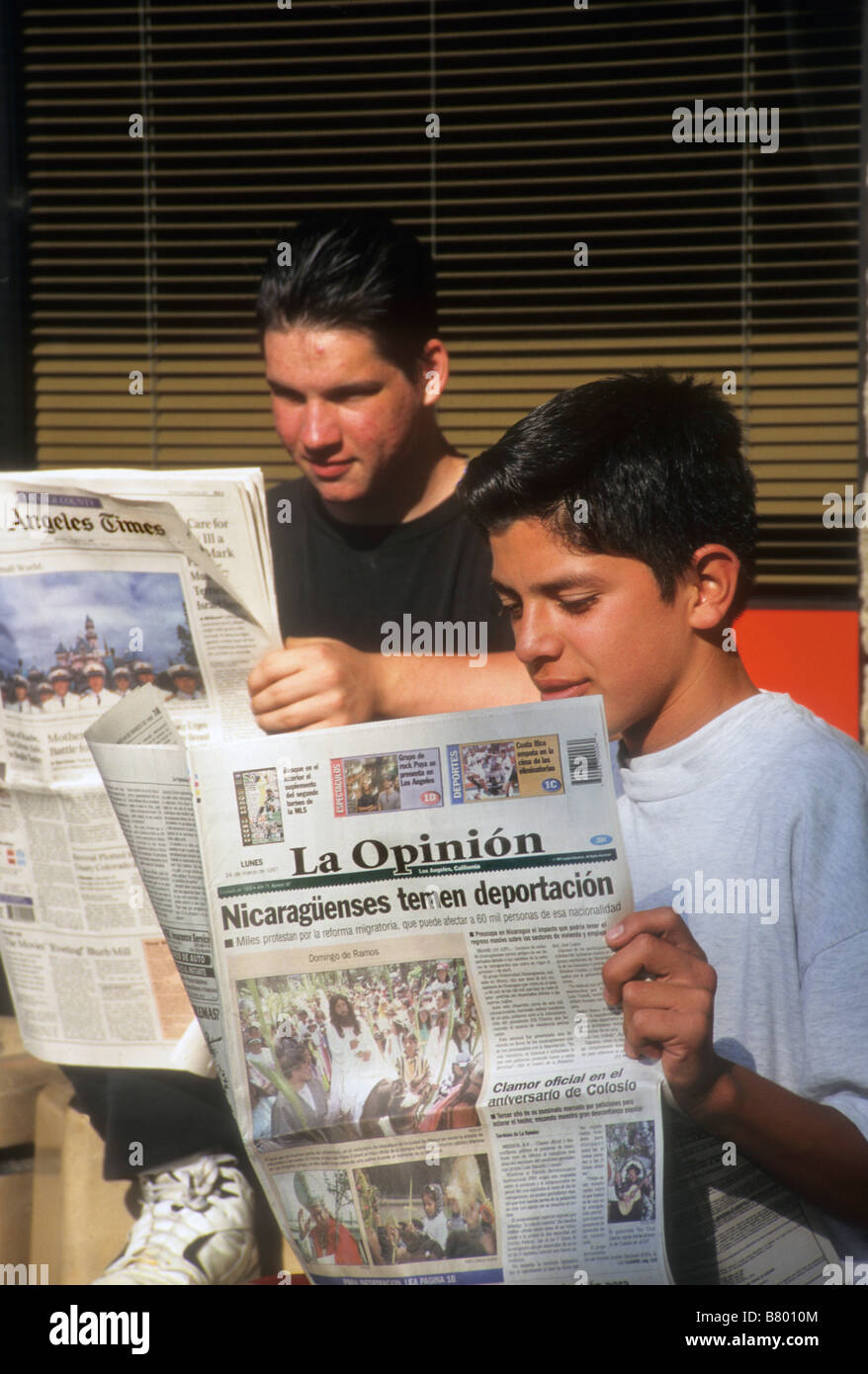 White boy reads English newspaper while Hispanic boy reads paper in Spanish los angeles times la opinion Stock Photo