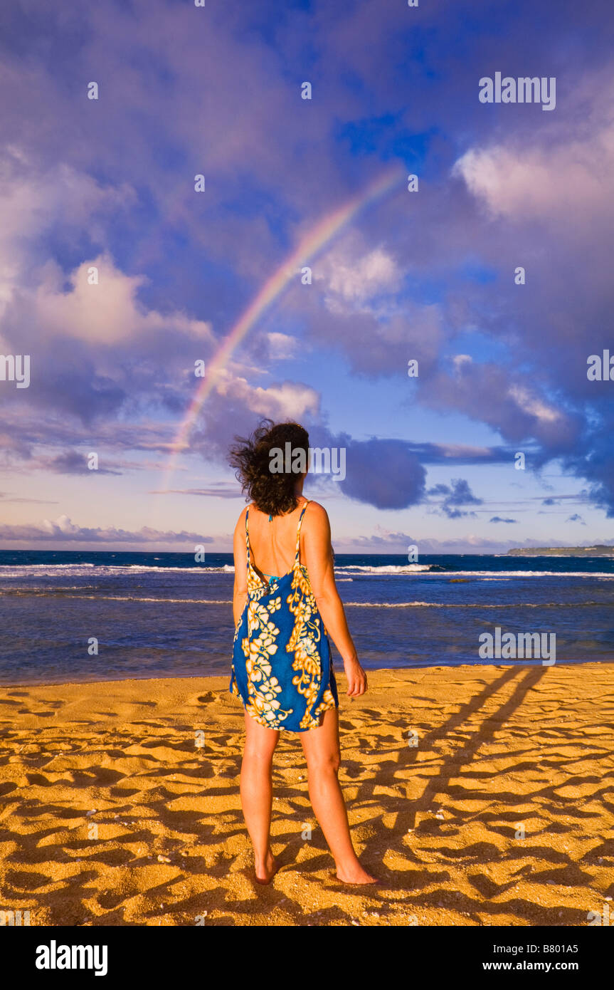 Rainbow over woman on Tunnels Beach at sunset Island of Kauai Hawaii