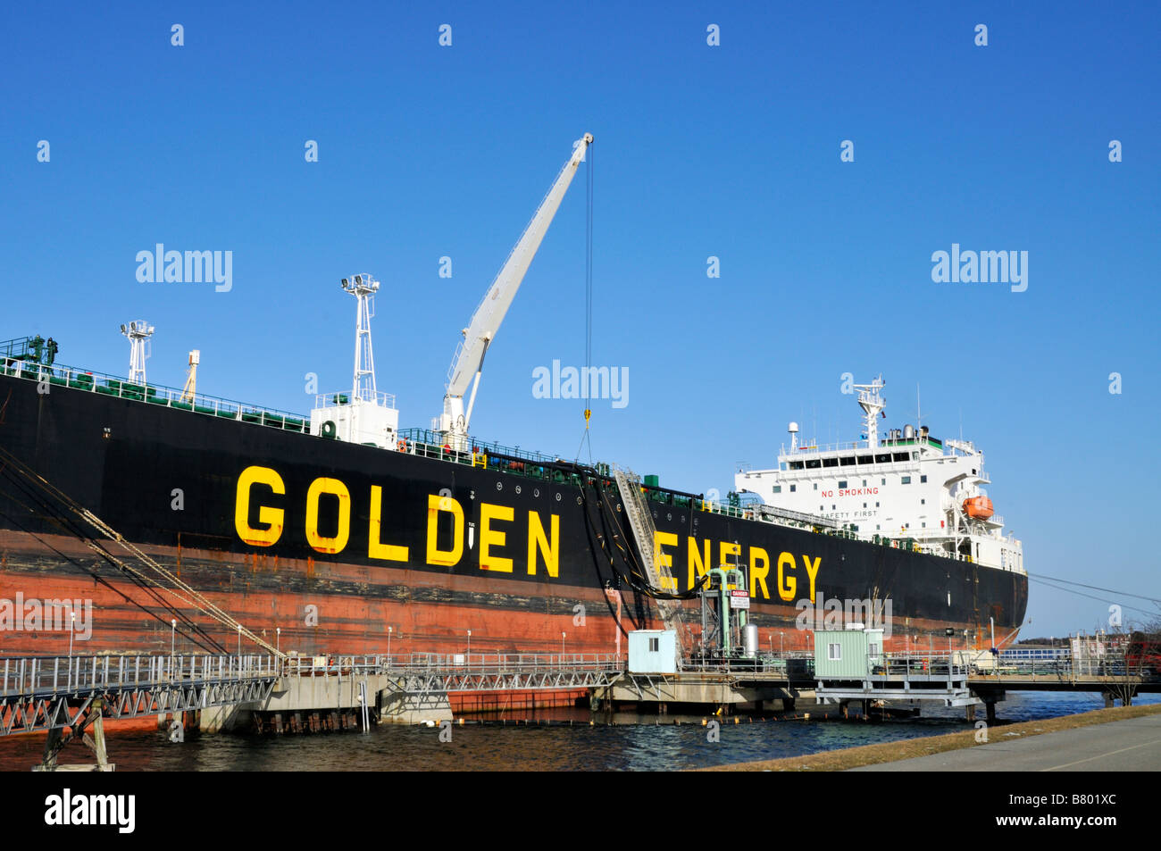 Fuel tanker Golden Energy  docked moored at marine terminal pier showing hose handling crane for offloading oil Stock Photo