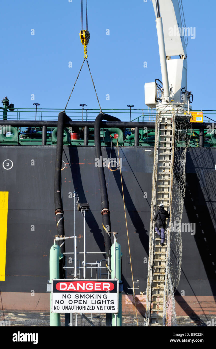 Offloading fuel from a tanker ship showing 2 hoses connected from ship