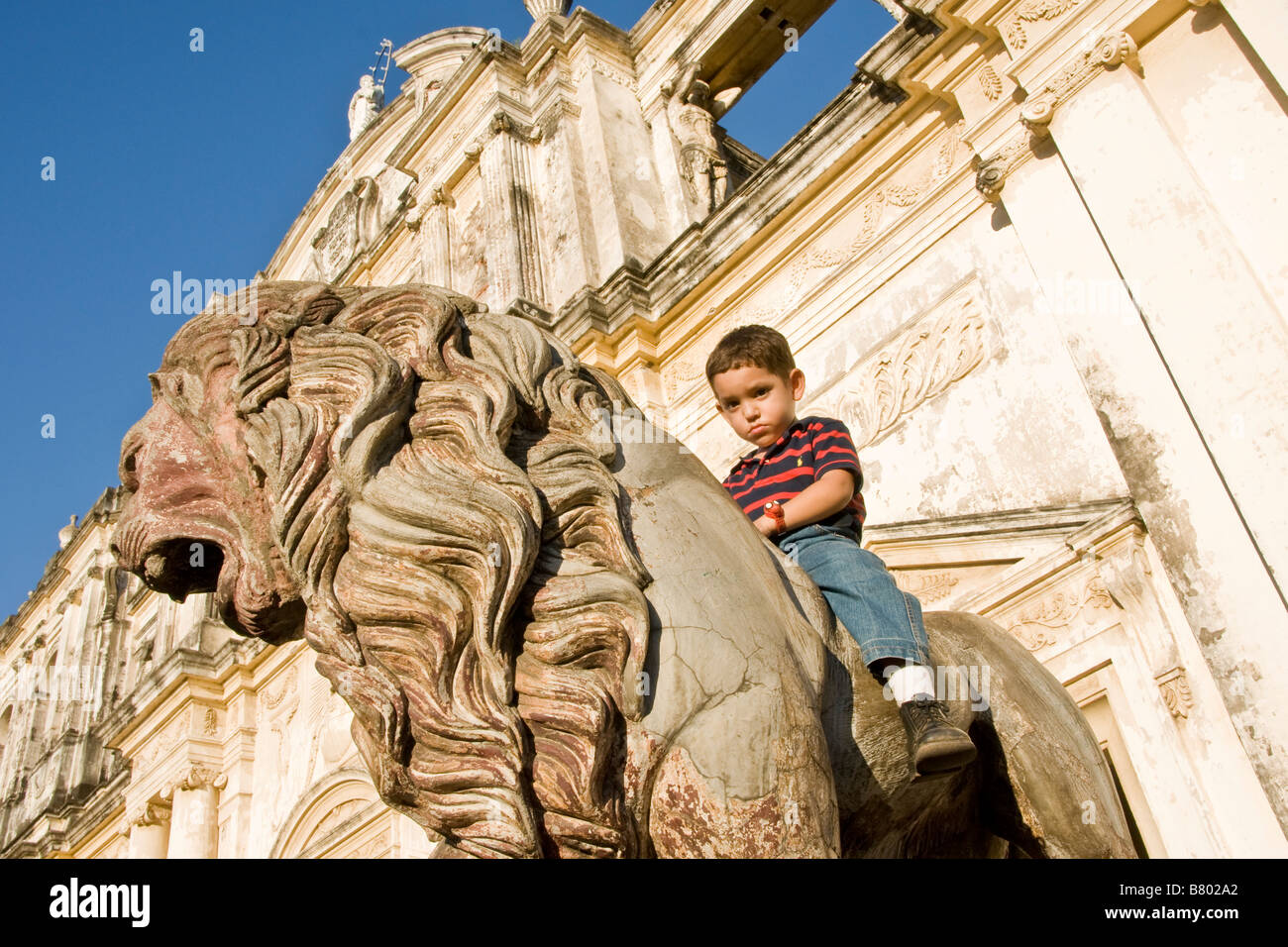 Leon Cathedral, Spanish colonial architecture, with Nicaraguan boy on lion statue flanking entrance Stock Photo