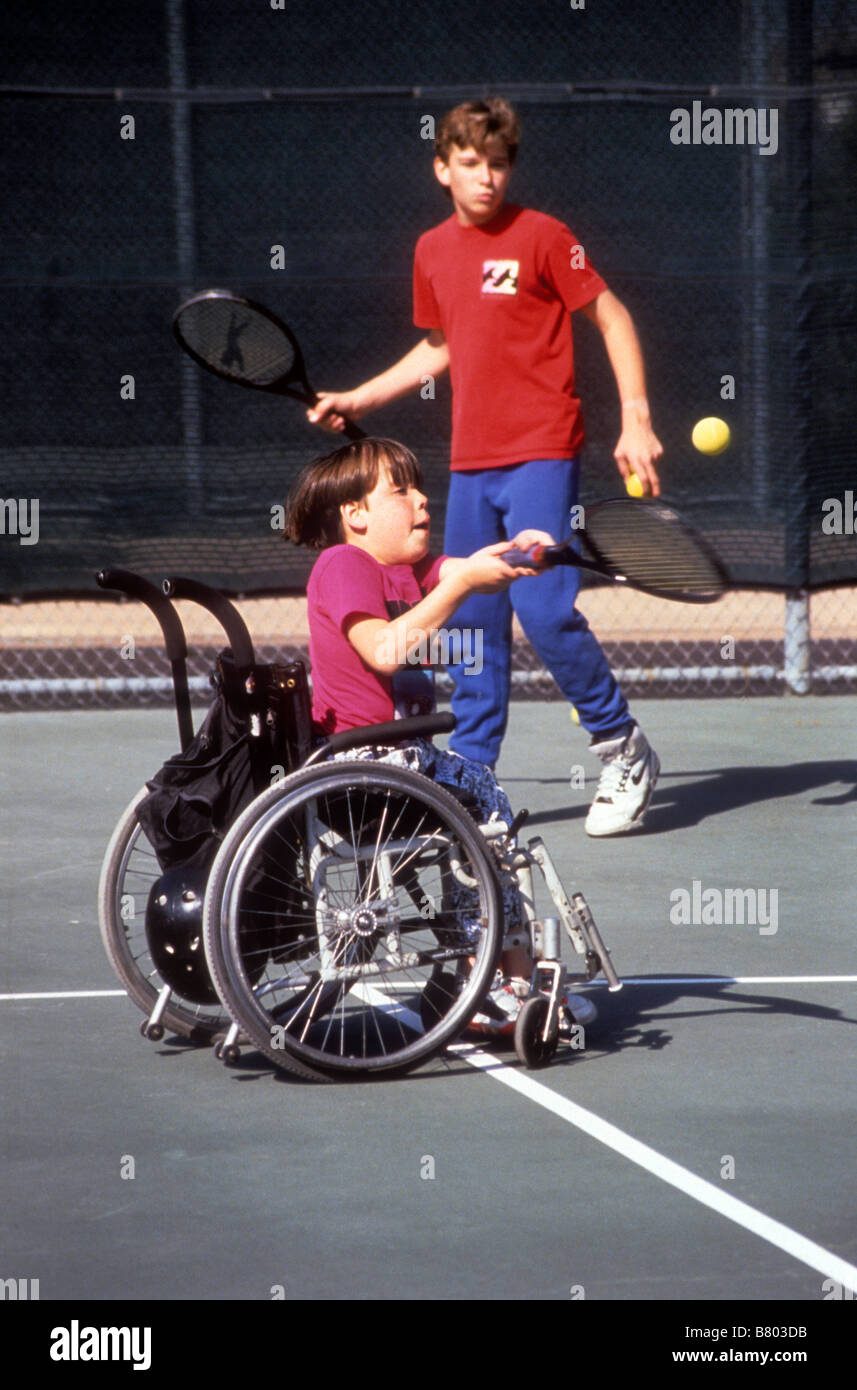 Handicapped boy learns to play tennis while in a wheel chair Stock Photo