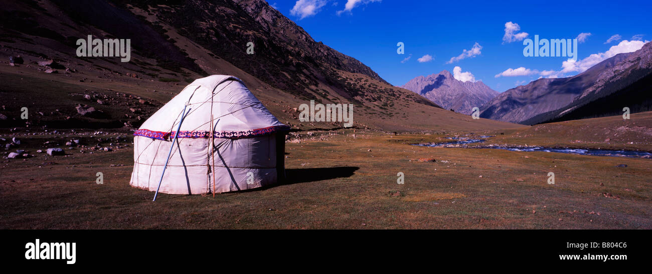 Panoramic image of a traditional Kyrgyz yurt against the backdrop of the majestic Tian Shan mountain range. Stock Photo