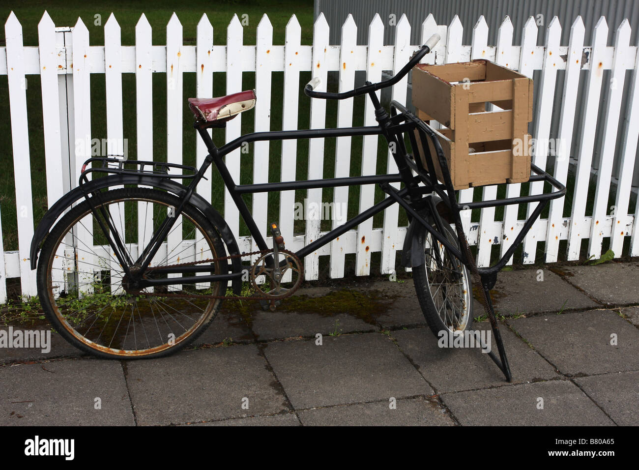 Old vintage bicycle standing by a white picket fence Stock Photo