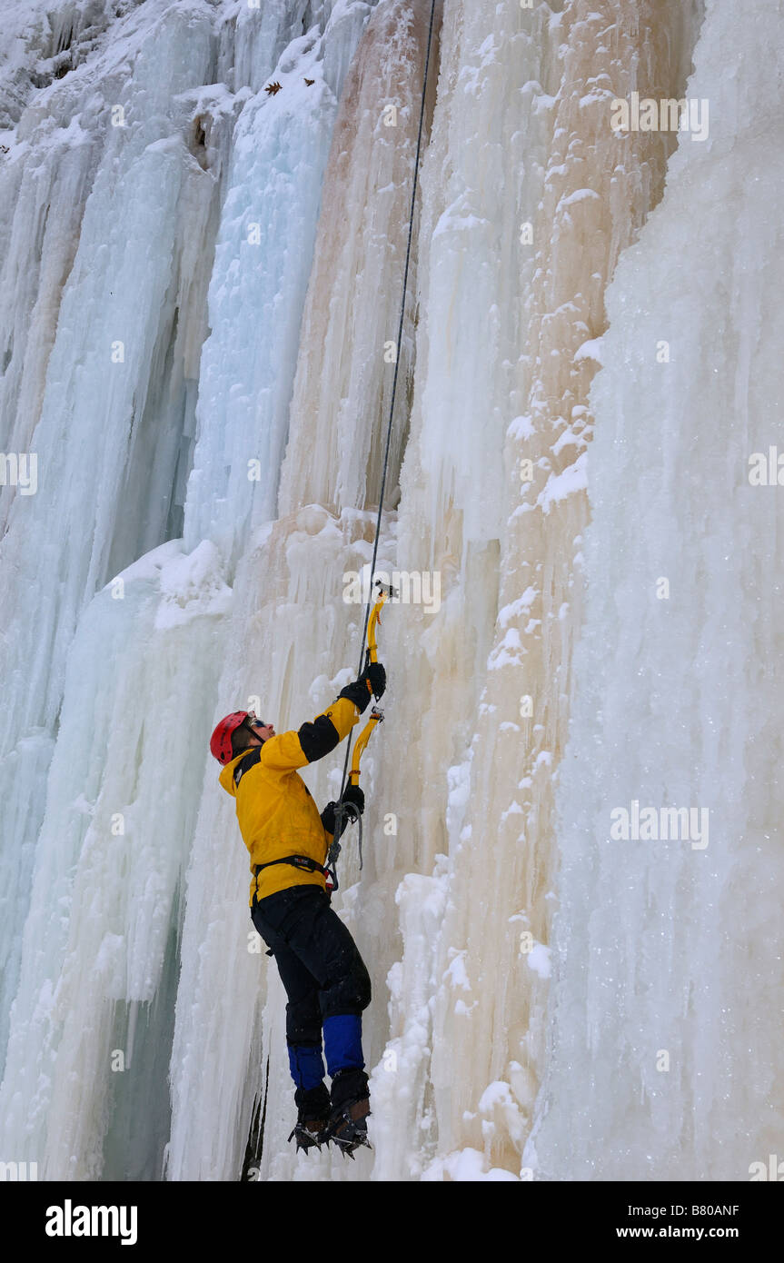 Ice climber looking up while front pointing up a steep wall of ice at Tiffany Falls Ontario Stock Photo