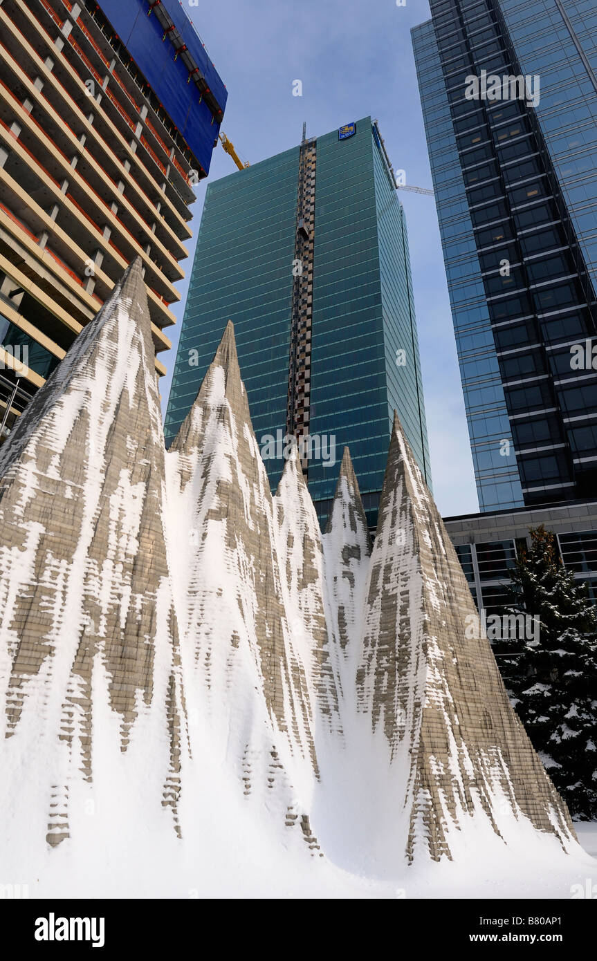 Highrise towers under construction in winter with snow covered aluminum mountain sculpture in Toronto Stock Photo