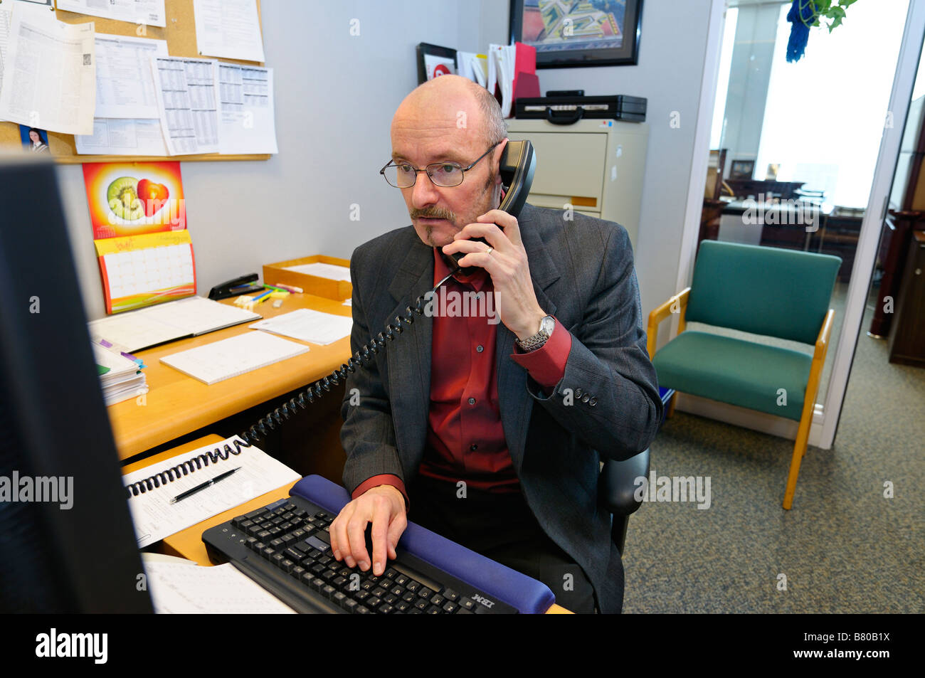 Male office manager working at desk on the phone and computer Toronto Canada Stock Photo