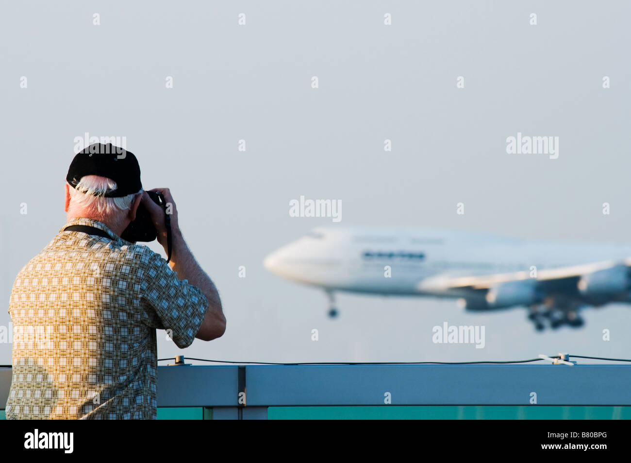 A man photographs an airplane landing at  Hong Kong Chek Lap Kok Airport from the sky deck. Stock Photo