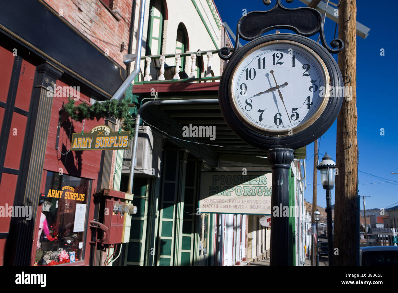 Shops with hanging signs a clock and a wooden boardwalk side walk line Main Street Virginia City Nevada Stock Photo