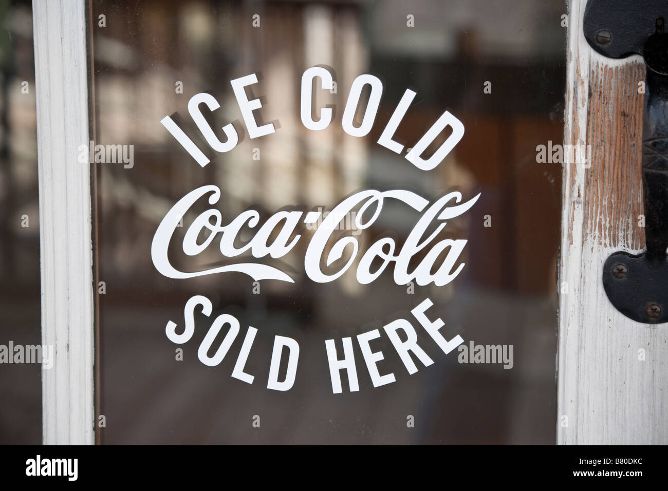 Ice Cold Coca-Cola Sold Here sign on old wooden door glass Stock Photo