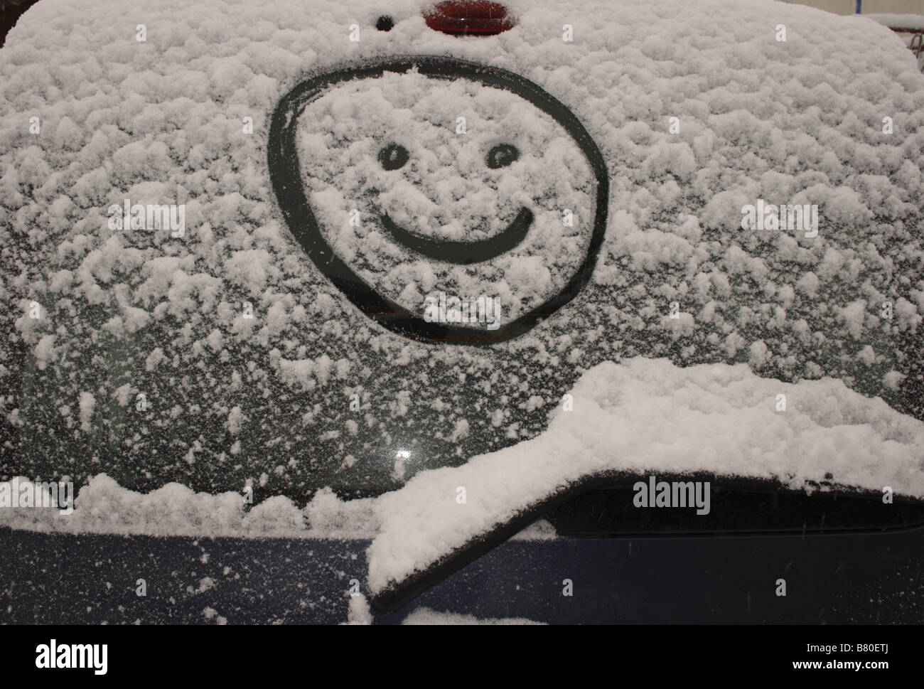 Smiley face drawn in fresh snow on rear windscreen of a car. Photo by Willy Matheisl Stock Photo
