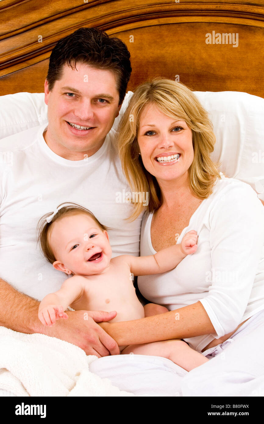 family of 3 sitting in bed portrait Stock Photo