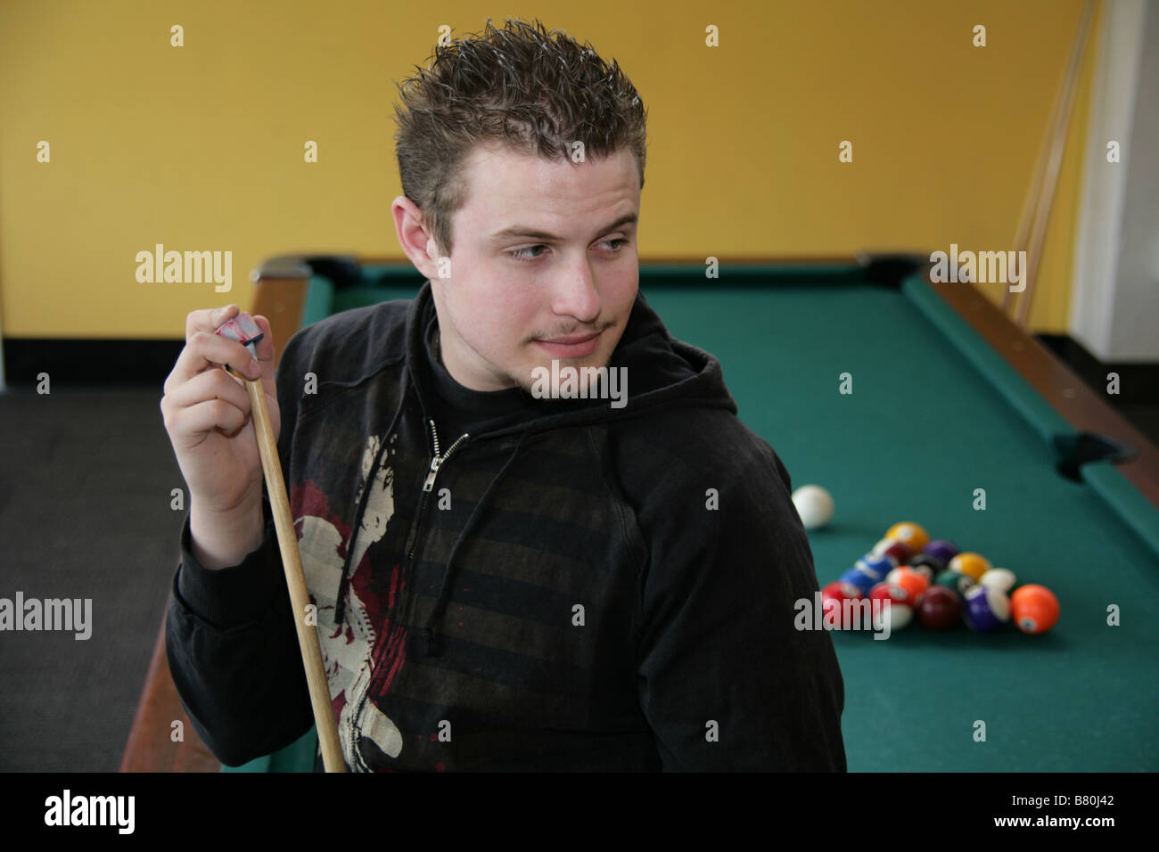 Young man chalking his pool stick Stock Photo Alamy
