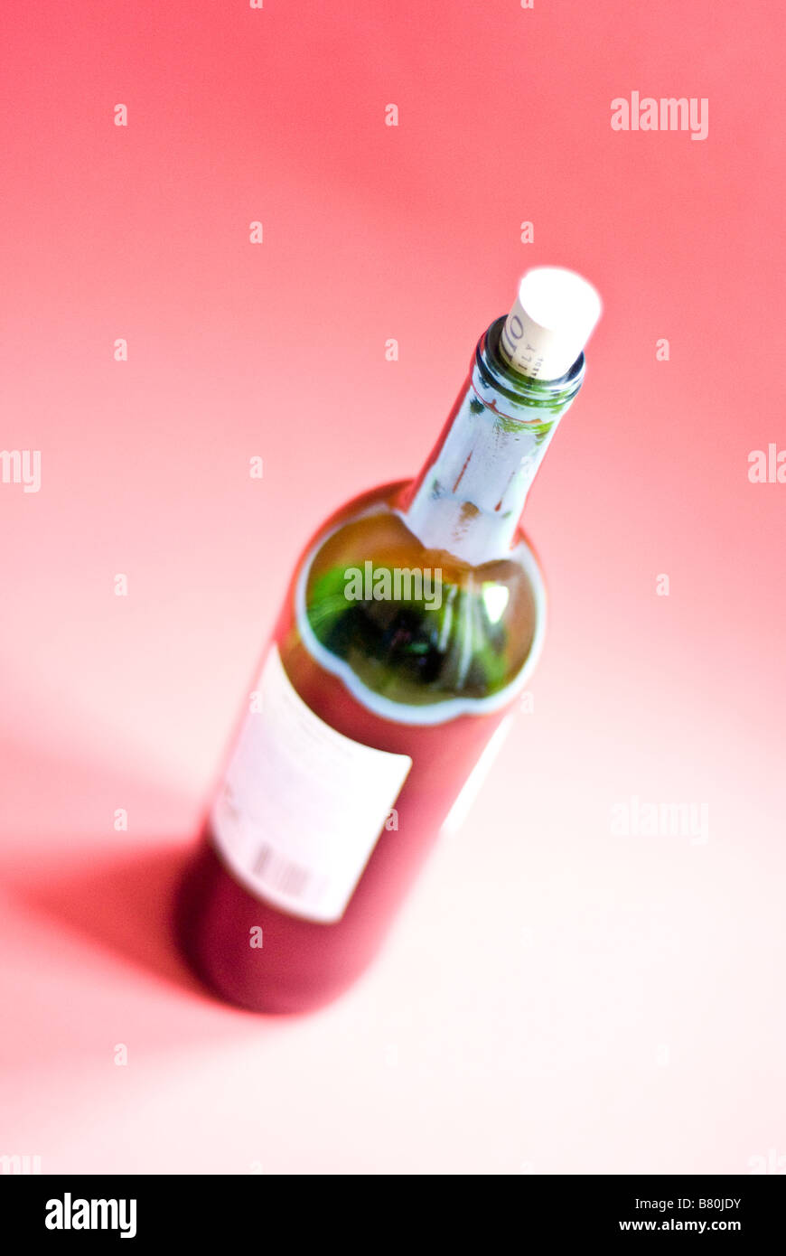Bottle of red wine on red background Stock Photo - Alamy