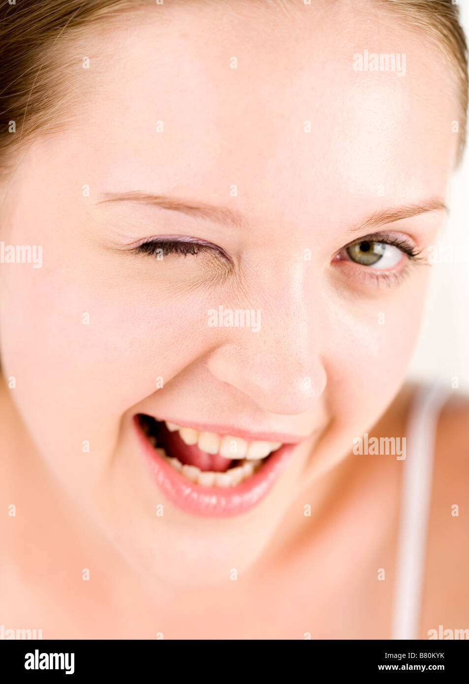Young woman blinking her right eye and smiling Stock Photo