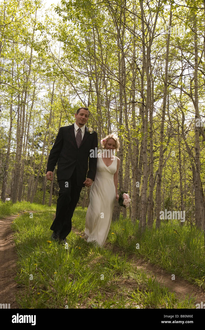 bride and groom walking through forest holding hands Stock Photo - Alamy