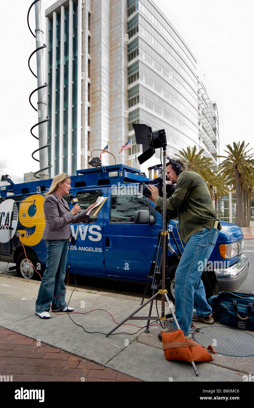 A television news reporter makes an on location broadcast from an immigrants rights demonstration in Santa Ana CA In background Stock Photo