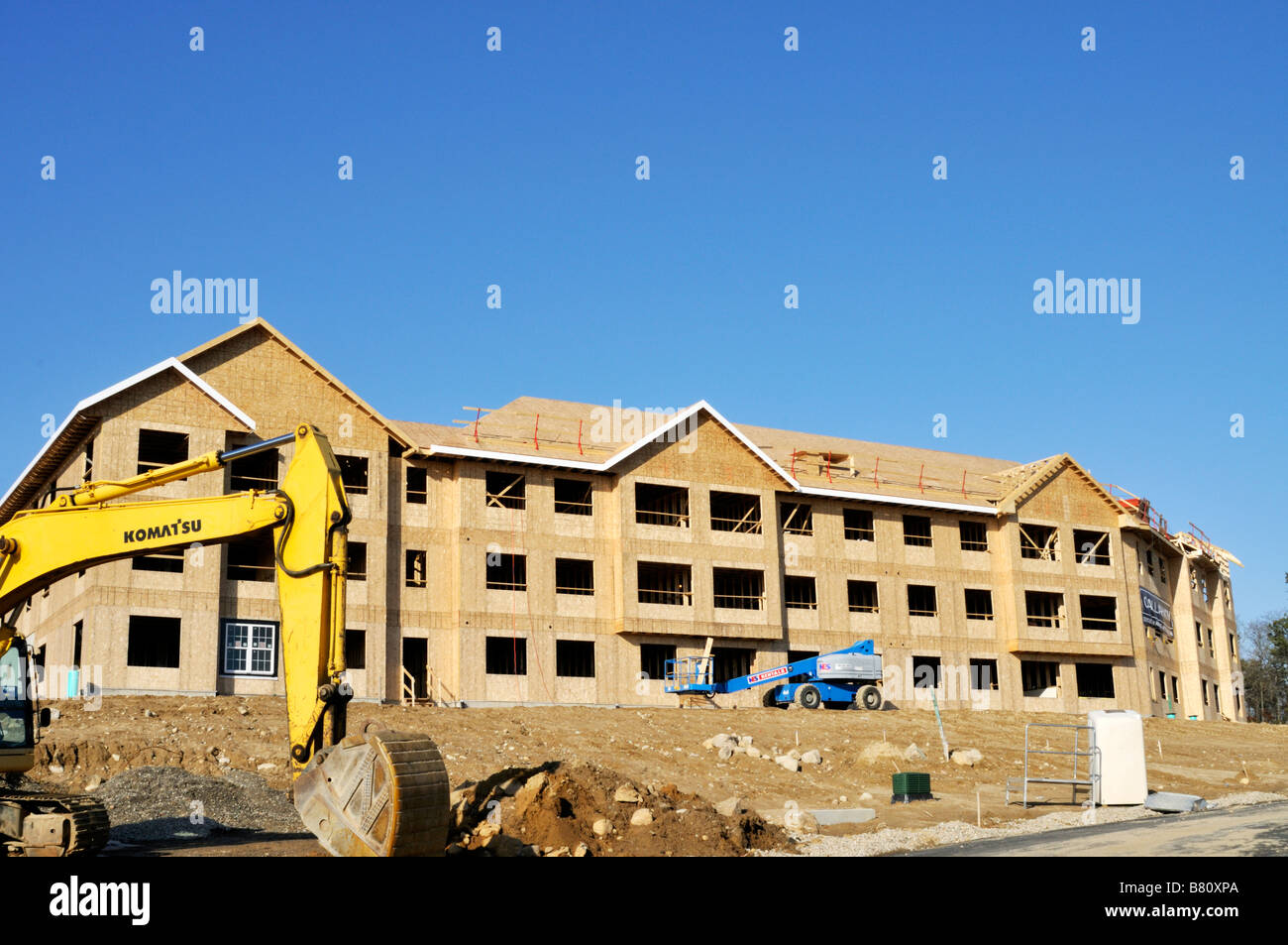 Apartment building construction site with the exterior wood frame and Komatsu excavator heavy equipment on site on Cape Cod, Massachusetts USA Stock Photo
