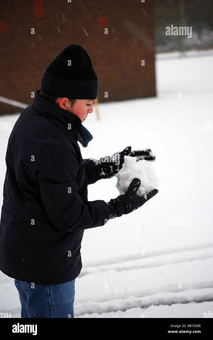 Rolling a Snowball to throw Stock Photo