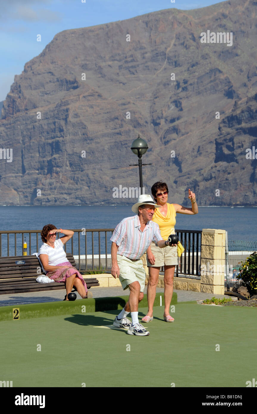 Holidaymakers seen during a bowls game at Los Gigantes Tenerife Canary Islands in the background the famous Cliffs Stock Photo