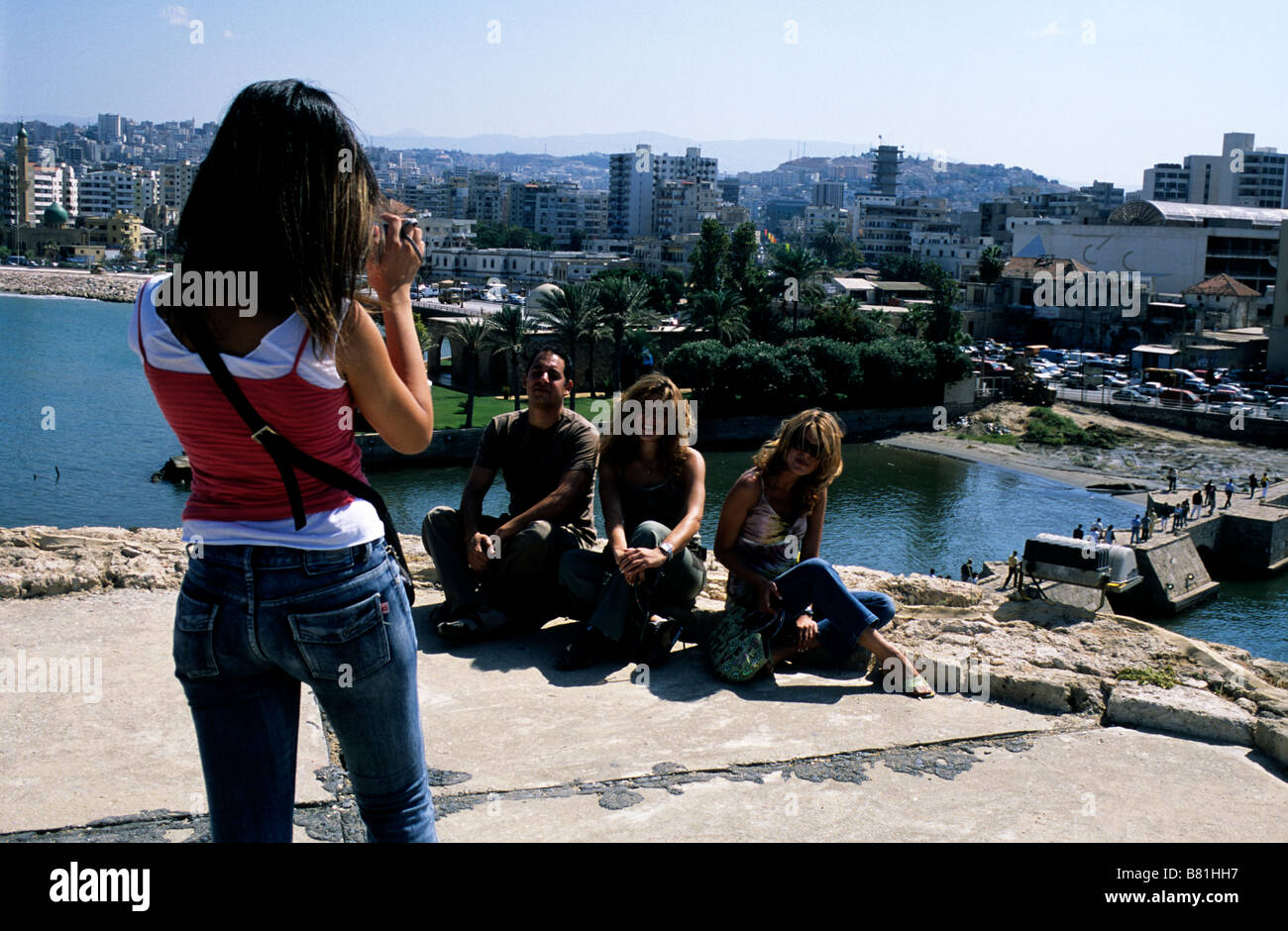 A young Lebanese woman takes a group photograph of her friends during a visit to the Crusader Sea Castle in Sidon, Lebanon Stock Photo