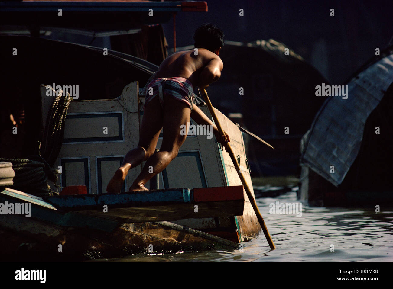 Poling a barge through the network of canals klongs bordering the Chao Phraya river near Bangkok Stock Photo