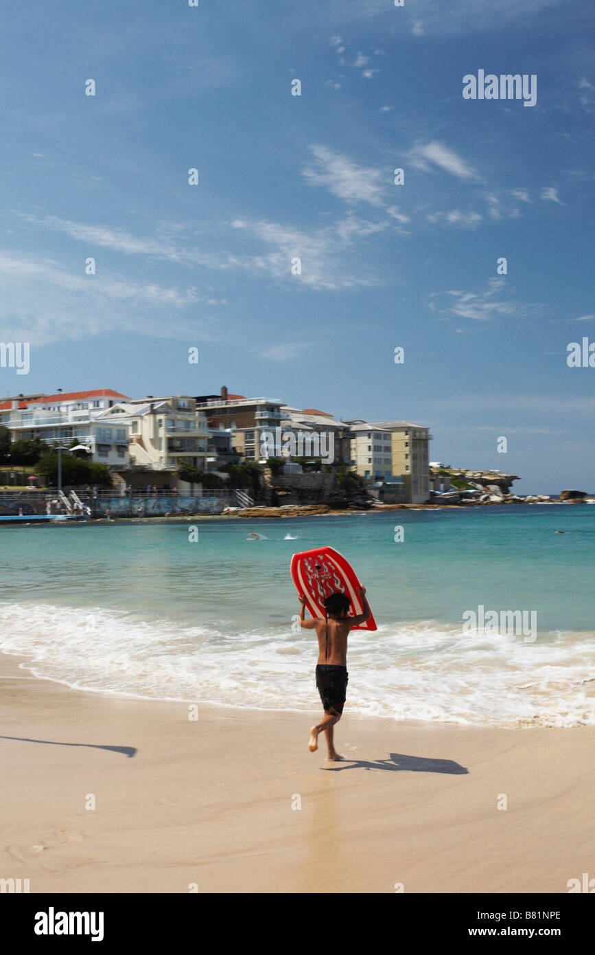 Boy 12 14 years running into the water at famous Bondi Beach Australia with his boogey board Stock Photo