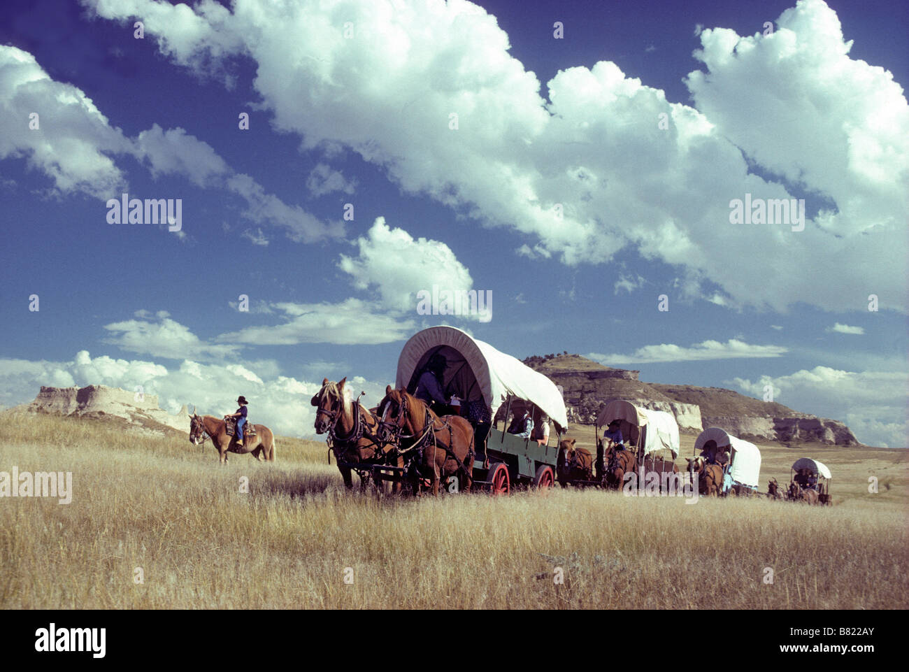 WAGON TRAIN AND OUTRIDERS CROSS THE NEBRASKA PRAIRIE; "OREGON TRAIL WAGON TRAIN", BAYARD