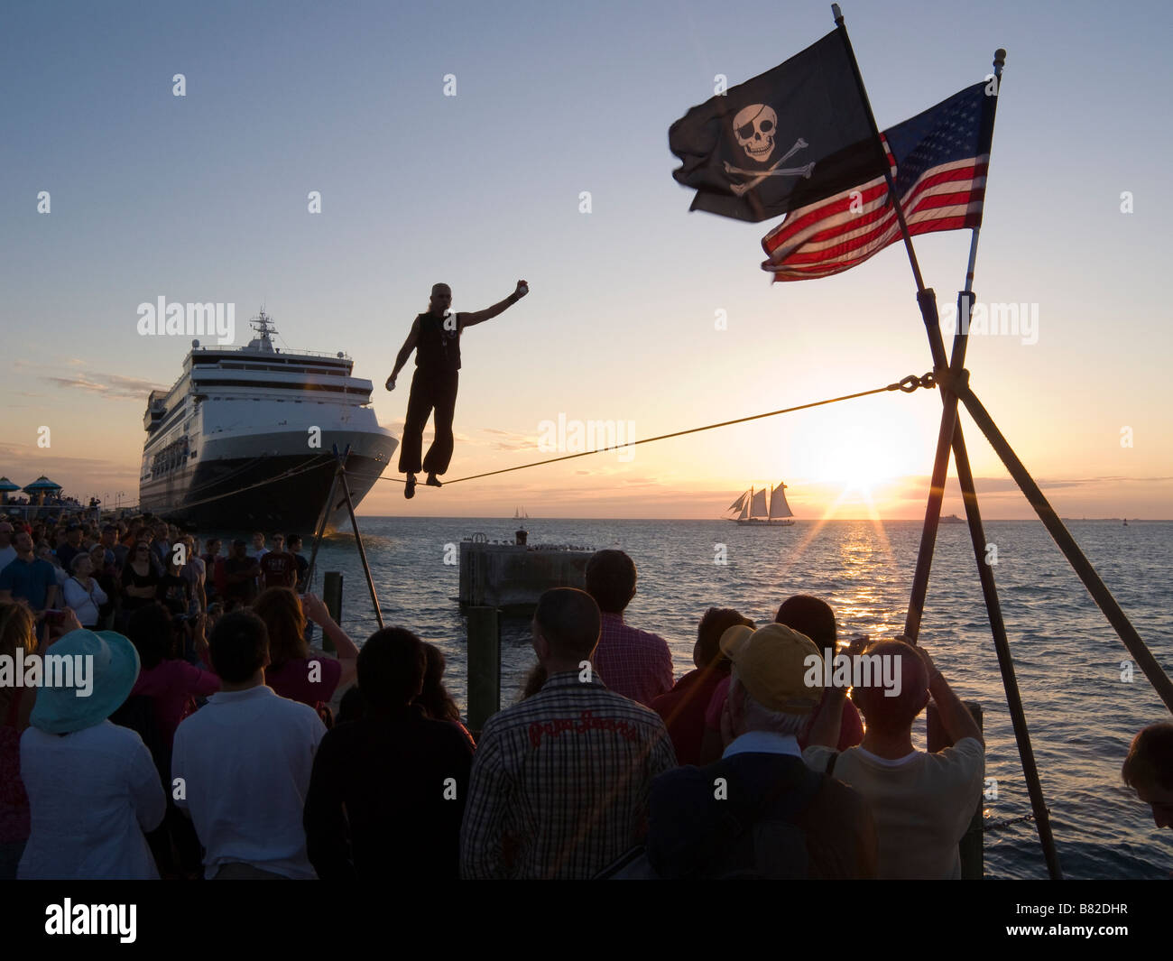 Tight rope walker juggles over ocean at sunset Mallory Square Key West Florida Stock Photo