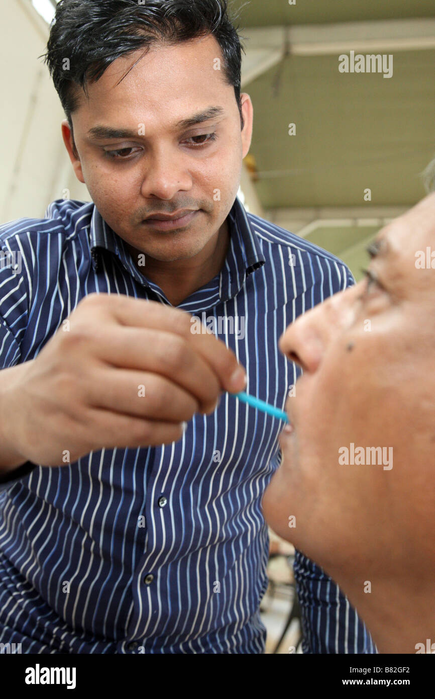 A medical practitioner takes a swab, or mucus sample from a patient Stock Photo