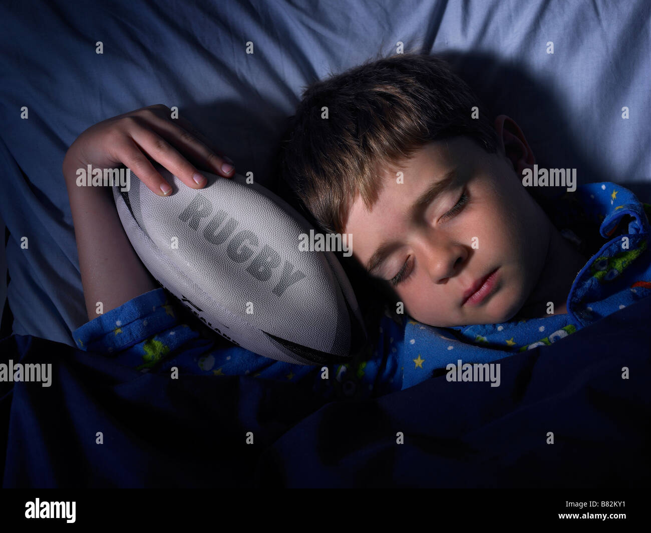 boy sleeping and dreaming of rugby grasping a ball Stock Photo