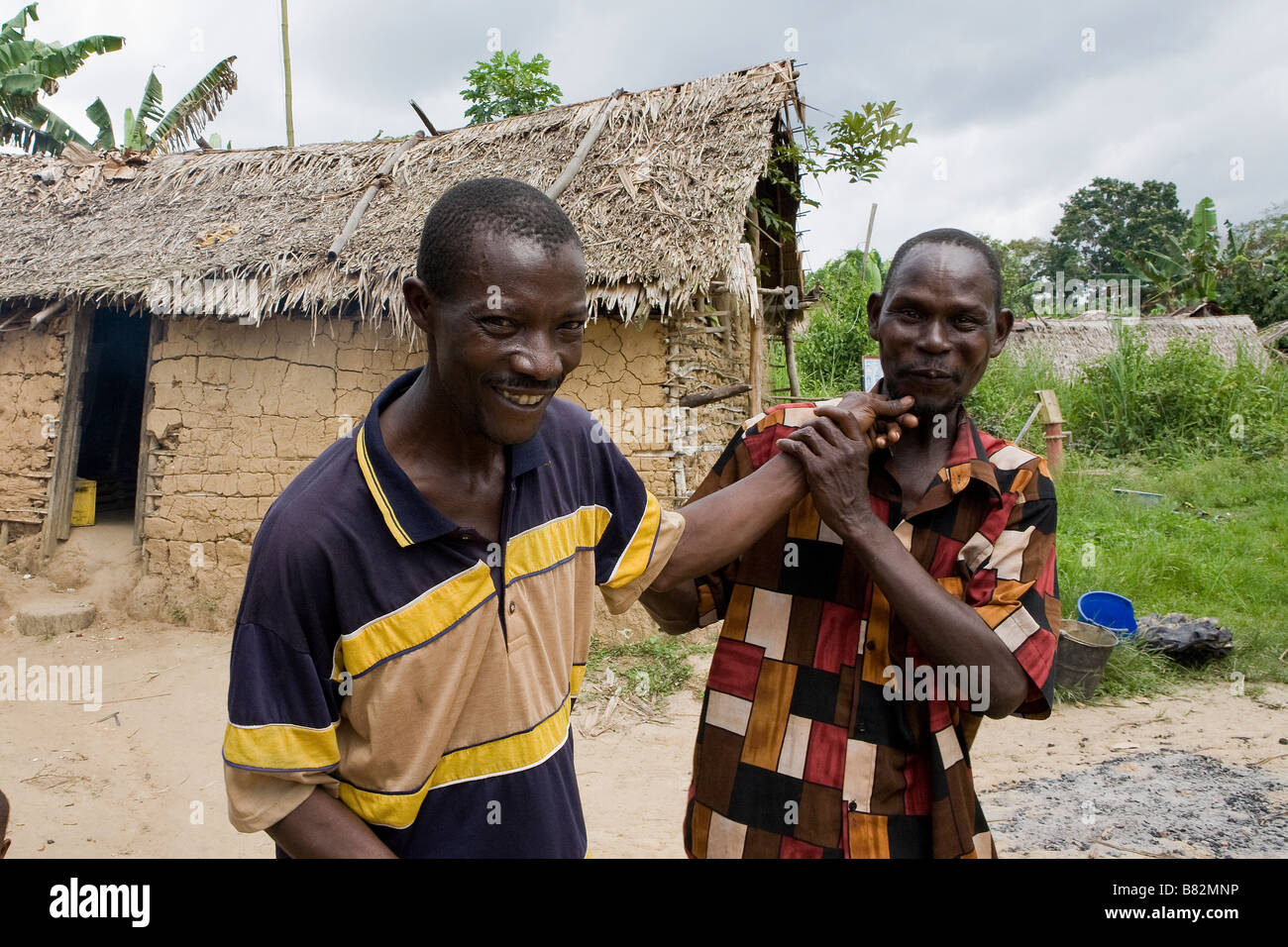 Two Nigerian men from a remote village in Epe mess about with the younger man tugging the beard of the elder Stock Photo