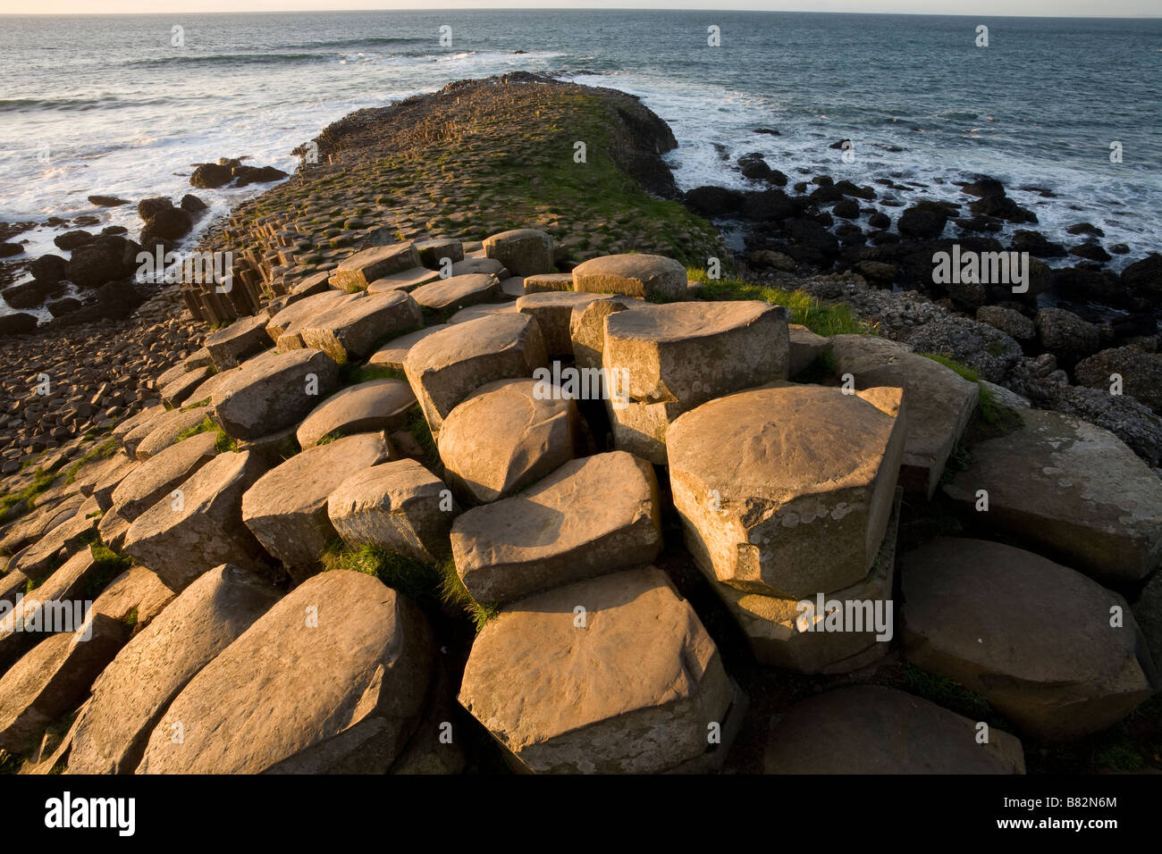 Causeway To Scotland Hexagonal Columns Of Basalt Glow In The Afternoon Sun As They Step Down Toward The Crashing Waves Stock Photo Alamy