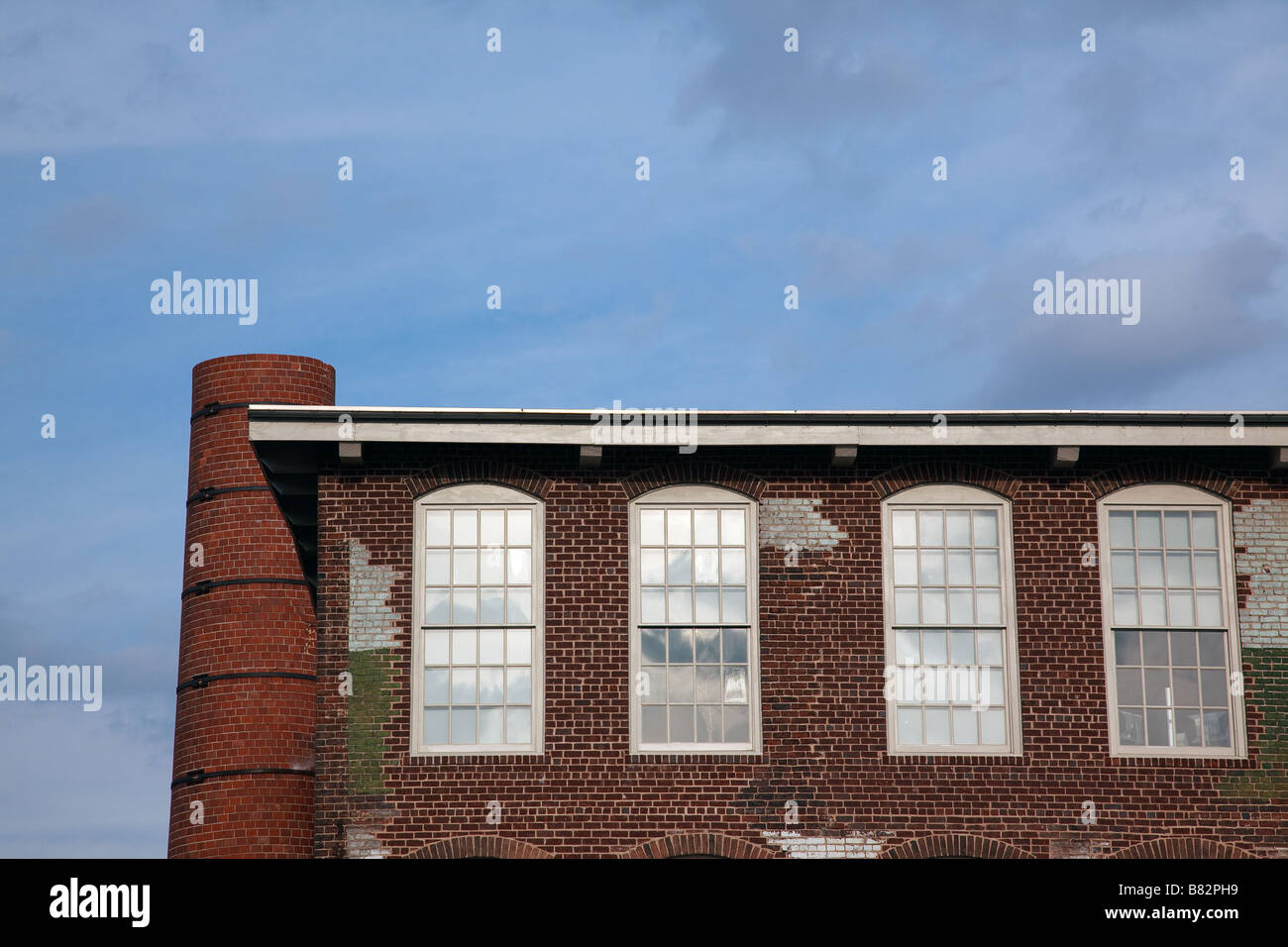 An old factory with detailed brick work sites with blue sky above perfect for copy space  Stock Photo