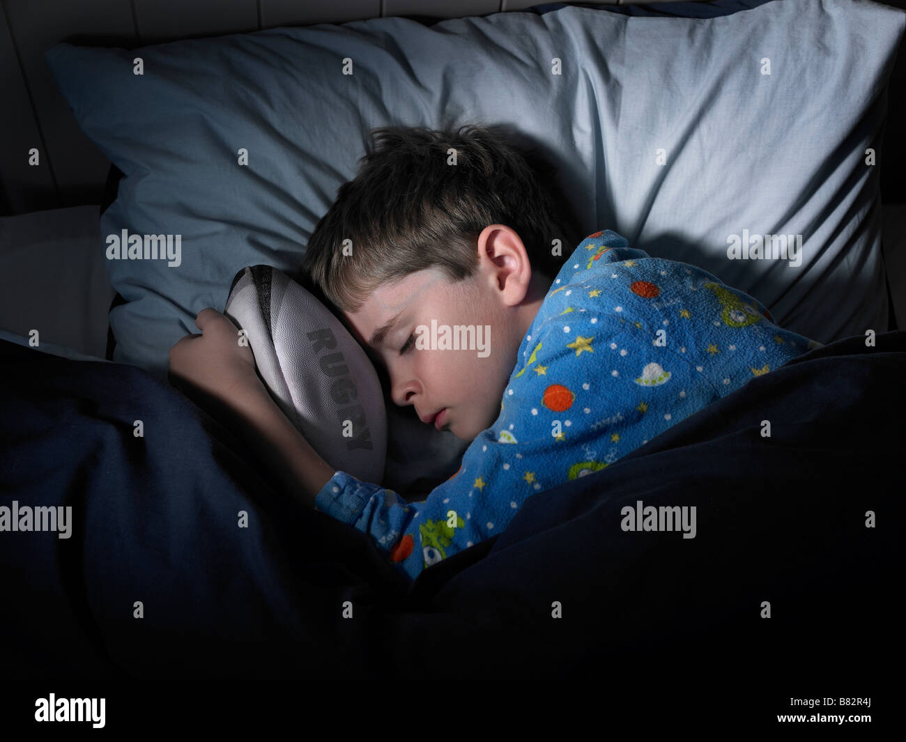 boy sleeping and dreaming of rugby grasping a ball Stock Photo Alamy