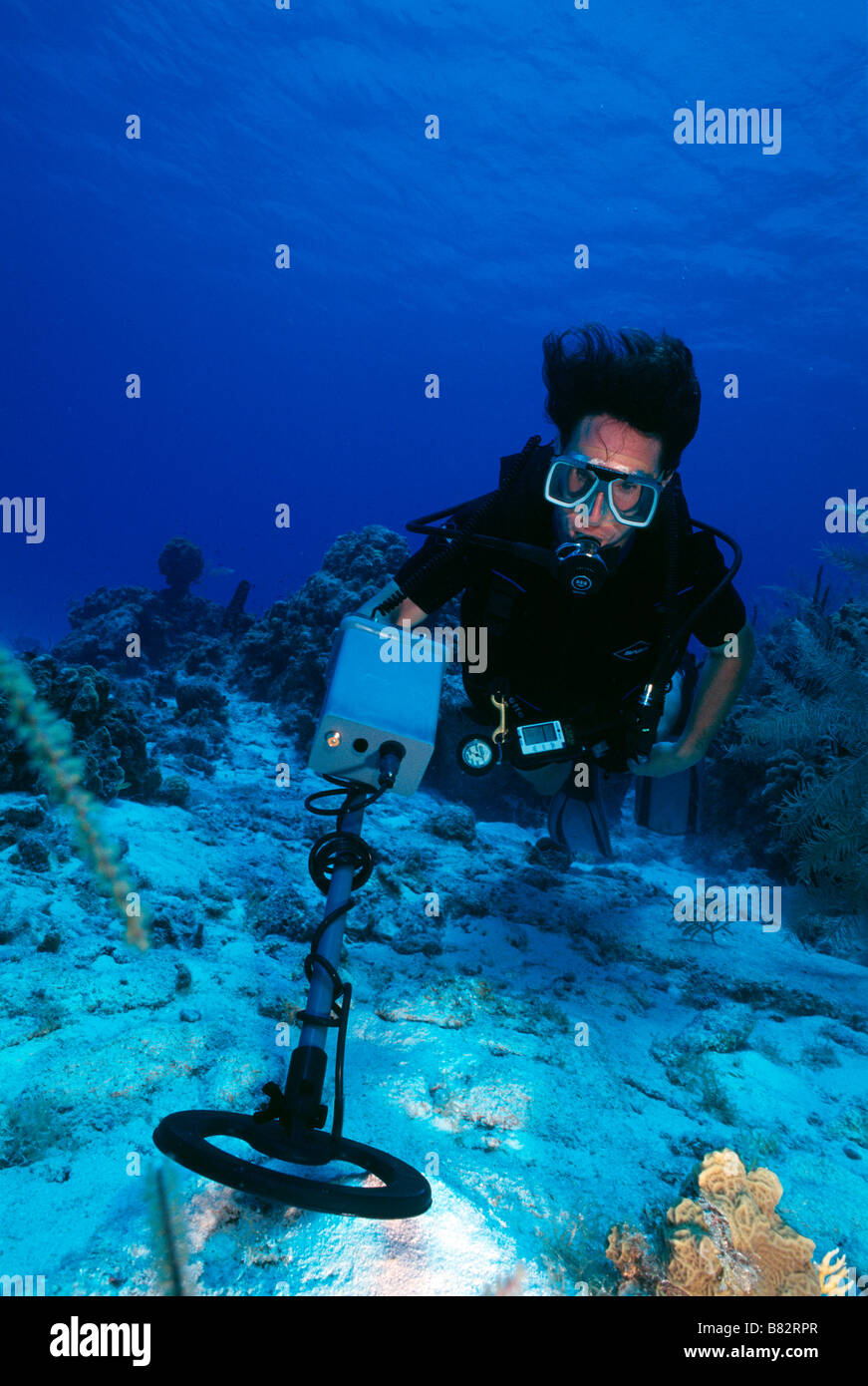 Diver with metal detector underwater, working, blue water, clear water