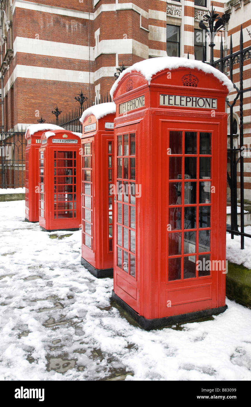 Four red telephone boxes in a row in snow Stock Photo