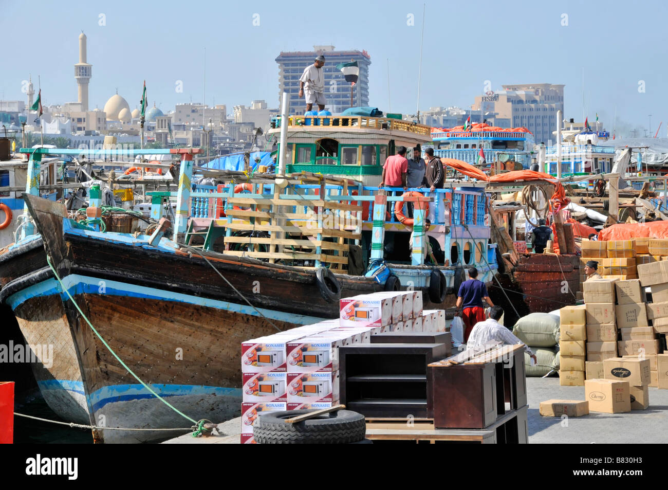 Dubai Creek seamen worker on dhows boat with imports exports  of merchandise on crowded congested port quayside United Arab Emirates UAE Middle East Stock Photo