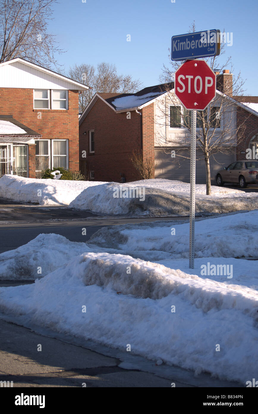 Dirty melting Snow on the side street/Road with Stop sign and Houses at the back in Scarborough Toronto Stock Photo