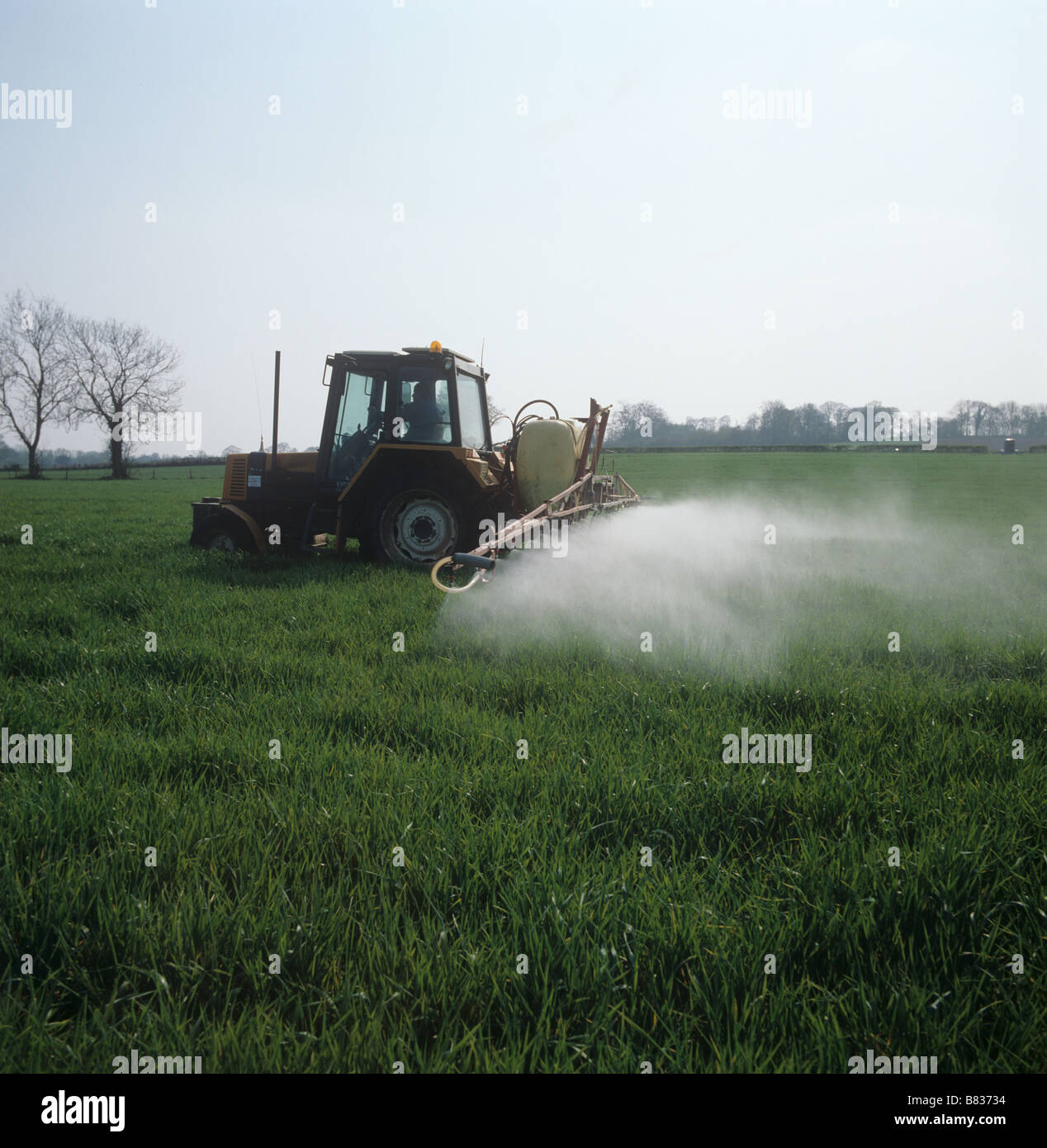 Renault tractor with a Hardi sprayer spraying a young barley crop in spring Stock Photo