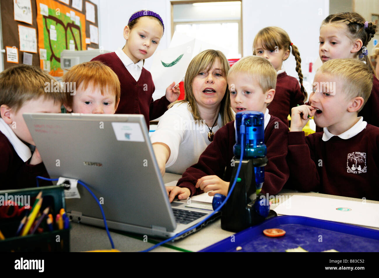 teacher working with primary school pupils on laptop computer Stock ...
