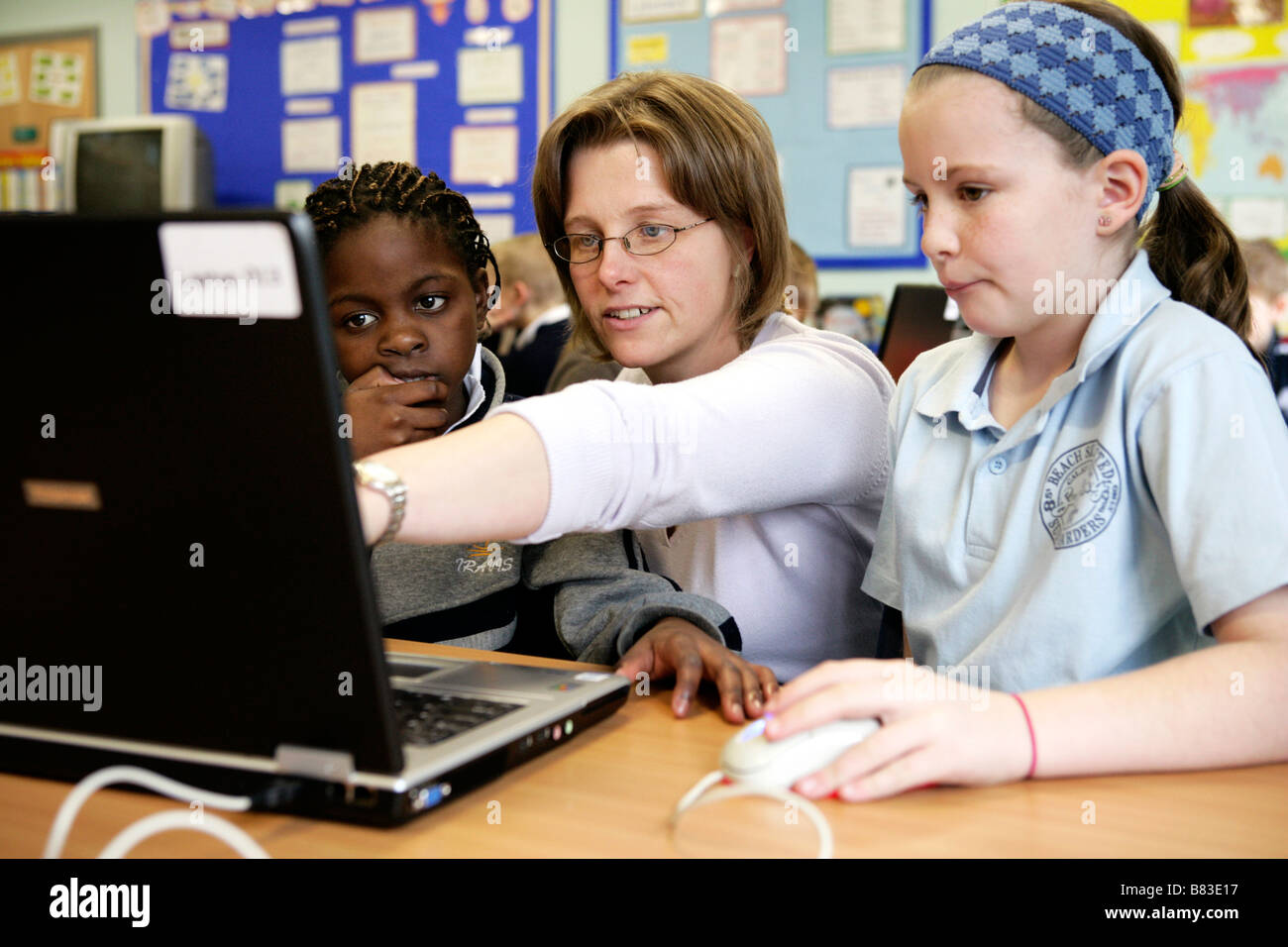 teacher working with primary school pupils on laptop computer Stock ...