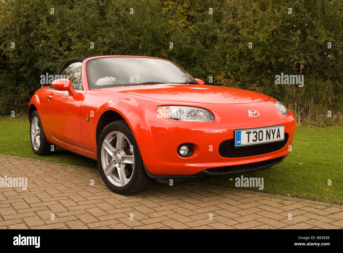 A red Mazda mx5 sports car parked on a drive outside a house Stock Photo