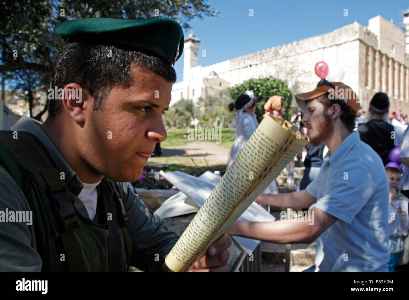 Israeli policeman reading a religious text during Purim celebrations in Hebron. Stock Photo